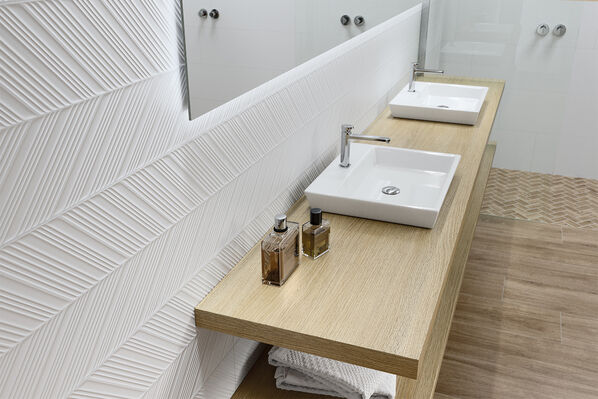Badezimmer mit zwei Waschbecken vor einer 3D-weiß gefliesten Wand.