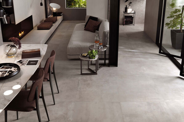 Fußbodenausschnitt, der mit der Bodenfliese Ceramicvision Evolution gefliest ist. Ebenfalls ist ein Teil einer grauen Sofagarnitur zu sehen. 