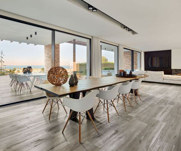 Wohnbereich mit großem Esstisch und Stühlen. Der Boden ist mit der Holzoptik Fliese Ceramicvision Silvis gestaltet.