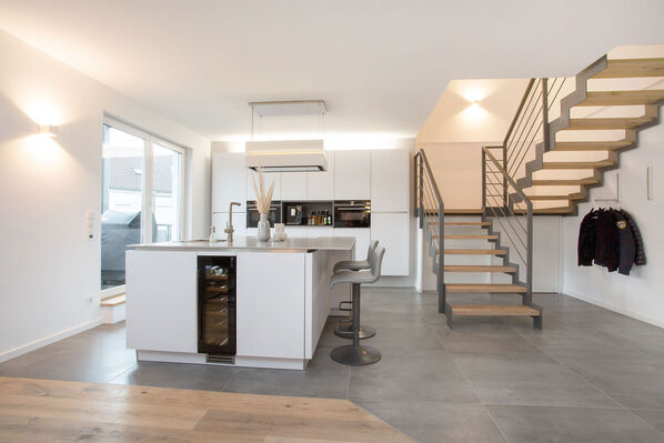 Moderne offene Küche mit Kochinsel. Die helle Küche setzt sich auf dem grauen Fliesenboden der Ceramicvision Blade ab. 
