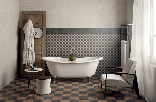 Badezimmer im Vintage Stil: Vor Kopf steht eine weiße Badewanne auf einem Fliesenboden. Dieser besteht aus schwarz-grauen Fliesen (Marca Corona Terra) im Schachbrettmuster.