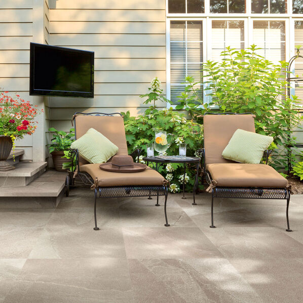 Terrassenausschnitt mit zwei darauf stehenden Liegen. Der Boden ist gefliest mit der Terrassenplatte Imola Ceramica X Rock Outdoor in der Farbe Beige. 