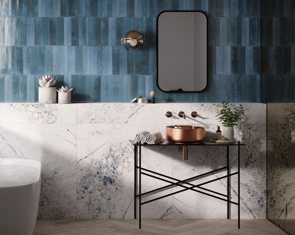 Badezimmerwand mit Waschtisch und Spiegel. Der obere Teil der Wand ist mit der blauen Fliese Dune Ceramica Agadir (Lago) und der untere Teil mit der Fliese Dune Ceramica Baikal Blue verkleidet. 