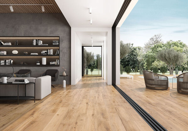 Wohnbereich mit einer großen Fensterfront auf der rechten Seite. Der Fußboden ist mit einer Fliese in Holzoptik (Keraben Naturwood) gestaltet. 