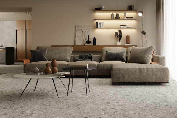 Wohnzimmer mit Couch und zwei kleinen Tischen. Der Boden ist im natürlichen Terrazzo-Stil gehalten (Atlas Concorde Boost Mix).
