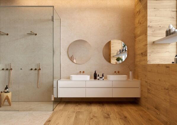 Modernes Badezimmer mit großem Waschtisch und zwei runden Spiegeln darüber. Boden und Wände sind mit Fliesen in Holz- und Steinoptik gestaltet (Marazzi Alba).