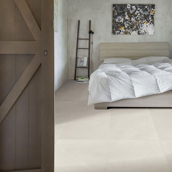 Schlafzimmer mit hellem Fliesenboden in weicher Betonoptik (Marazzi Apparel).