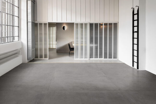 Heller leerer Büroraum mit grauem Fliesenboden, Marazzi Cementum, in Betonoptik.