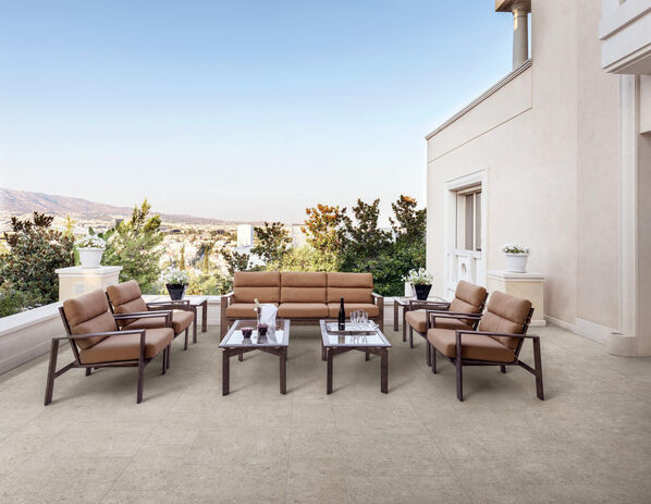 Terrasse mit Holztisch und Stühlen. Der Boden ist mit der sandfarbenen Steinfliese Marazzi Caracter in der Farbe Blanco gefliest. 