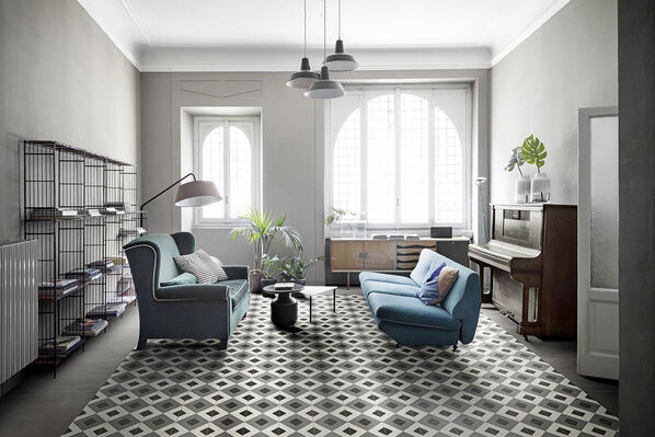 Wohnzimmer mit Teppichmuster auf dem Fußboden, das mit der Marazzi D_Segni Fliesen gestalttet ist. 