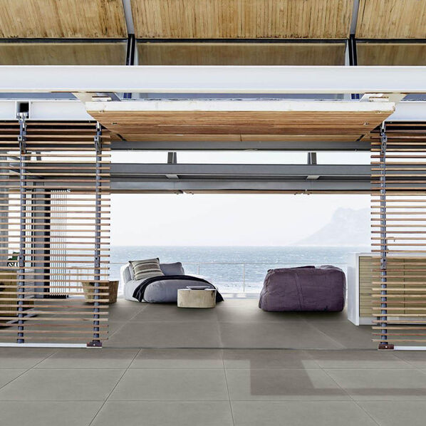Wohnbereich mit angrenzender Terrasse. Der Boden ist mit grauen Terrassenplatten in Betonoptik gestaltet (Marazzi Material20).