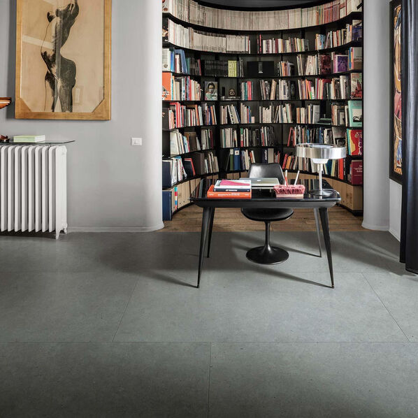 Arbeitszimmer mit grau gefliestem Fußboden in Steinoptik (Marazzi Mystone Moon), Bücherschrank und Schreibtisch.