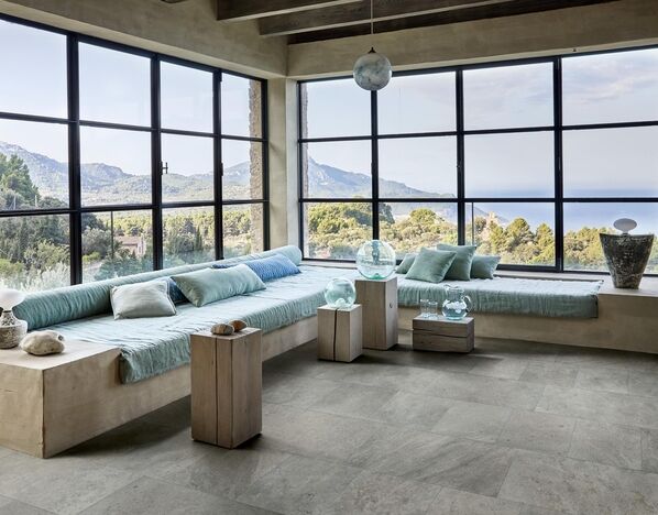 Großer Wohnraum mit Panoramablick auf die Landschaft und das Meer. Der Boden ist mit Fliesen in Natursteinoptik gestaltet (Marazzi Uniche).