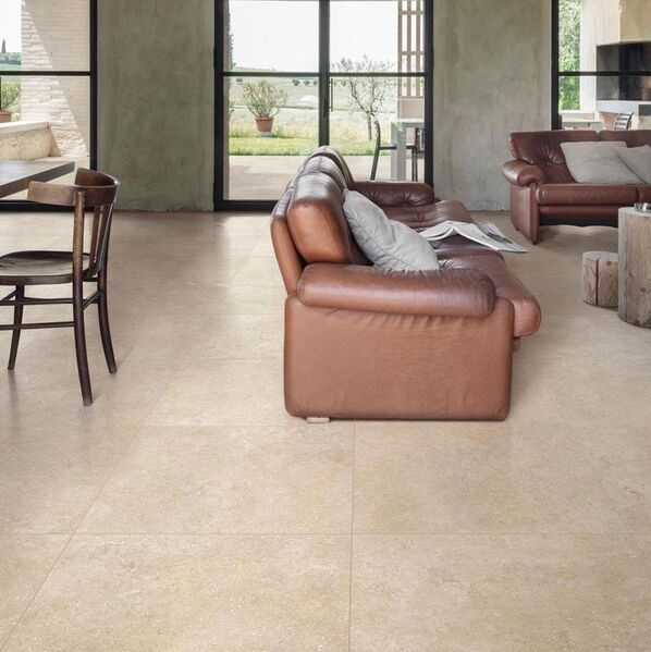 Wohnzimmer im warmen Braun- und Beigetönen. Der Boden ist mit der Marazzi Mystone Limestone in warmer Steinoptik gefliest.