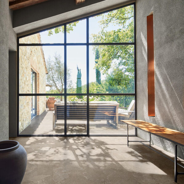 Großer Lofraum mit großer Fensterfront, der mit der Marazzi Mystone Pietra Ligure in der Farbe Beige gestaltet wurde. 