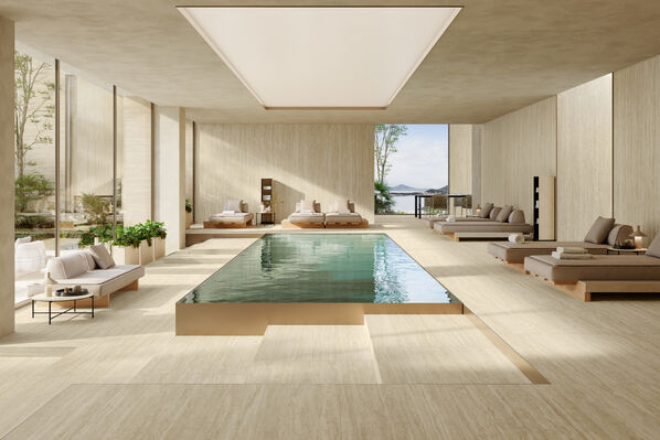 Großer heller Wellnessbereich mit in der Mitte platziertem Pool. Der Boden wurde mit Fliesen - Atlas Concorde Marvel T Romano Sand - in Travertinoptik gestaltet. 